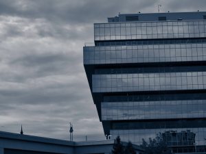 A glass office building against a cloudy sky.